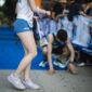 Runners cross the finish line at a marathon event in a city park. Participants rejoice and celebrate their achievements while others show signs of fatigue after the race.